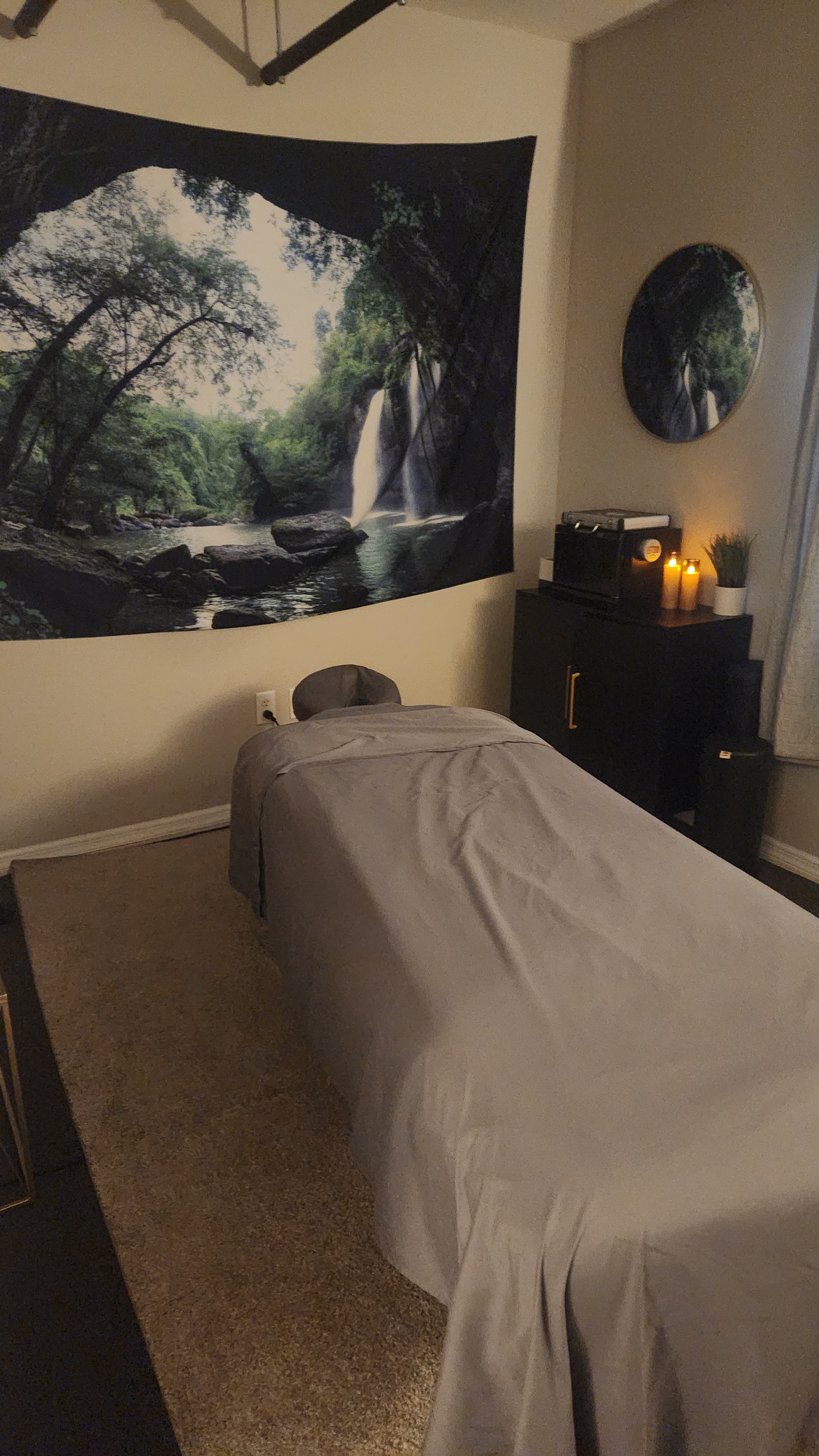 Calm treatment room with candles and a waterfall tapestry
